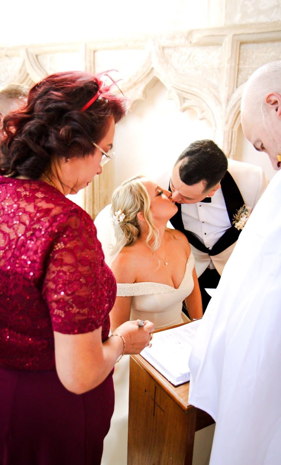Newlyweds kissing as the register is signed in church