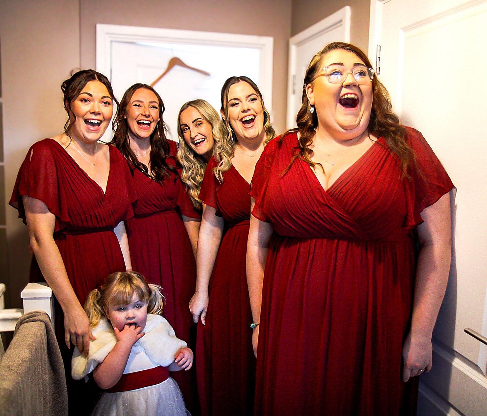 Bridesmaids in red laughing together before the ceremony