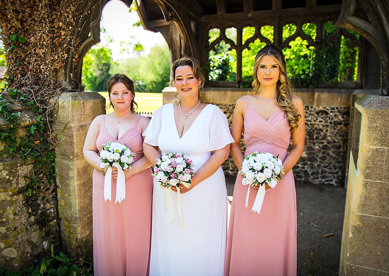Bride with her bridesmaids under a church lychgate