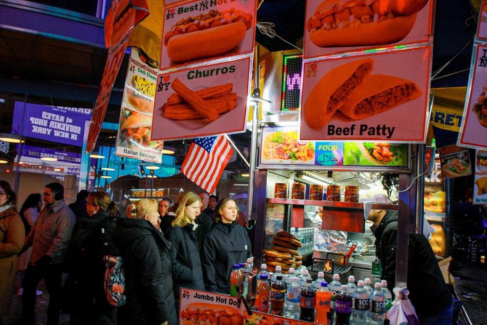 New York hot dog cart glowing under its signs at night