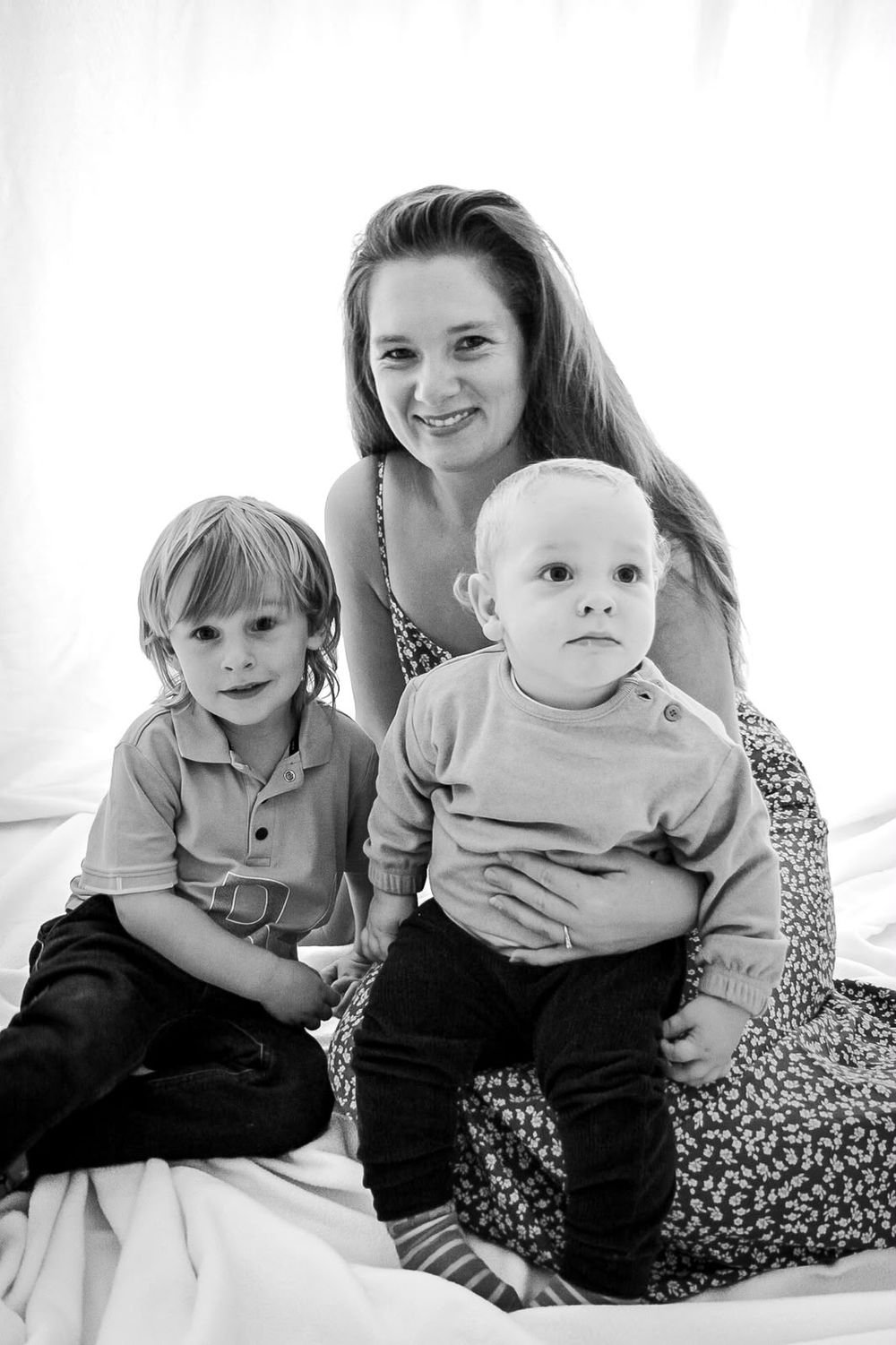 Mother with her two young sons in a bright studio family portrait, black and white