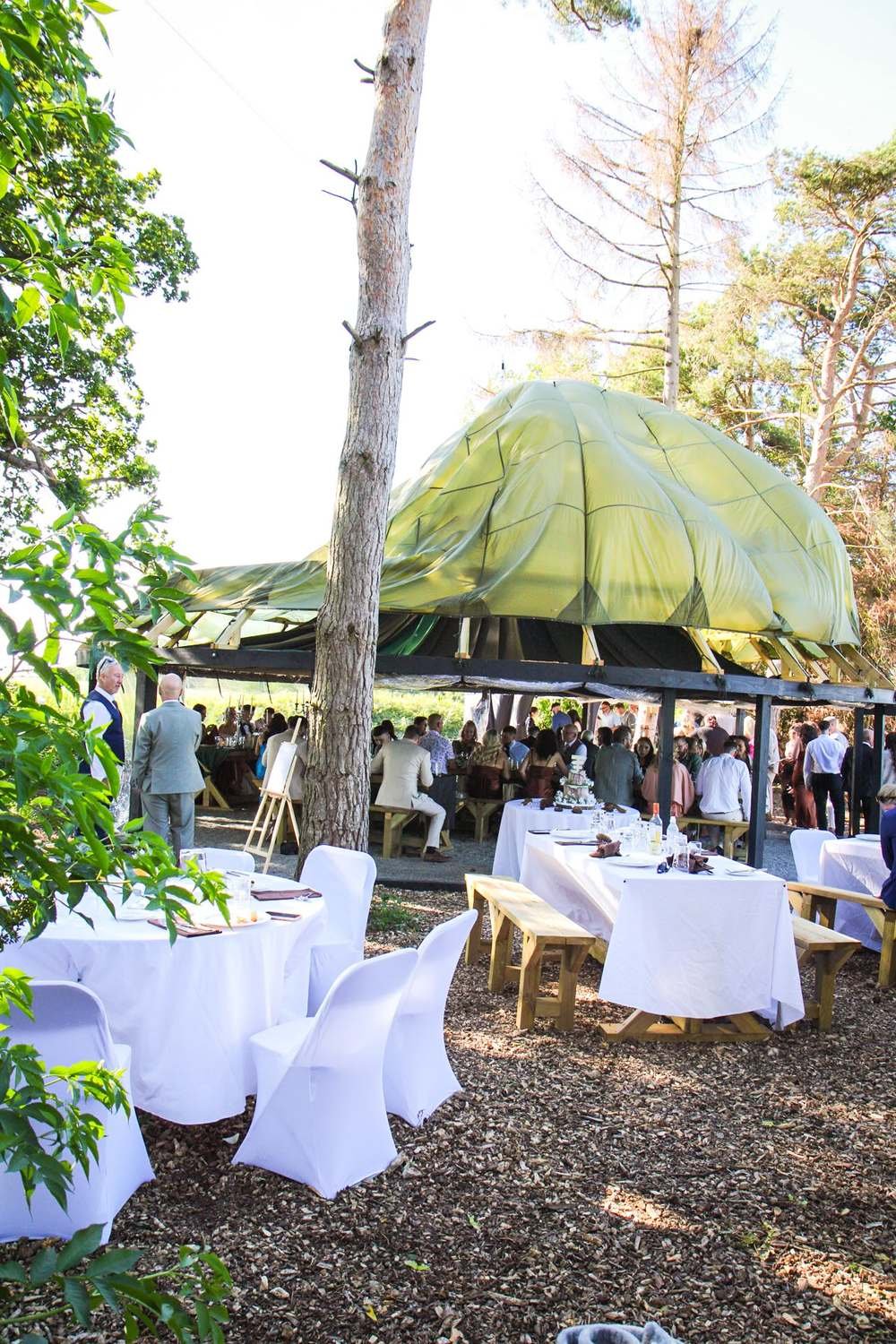Woodland wedding reception under a draped parachute canopy