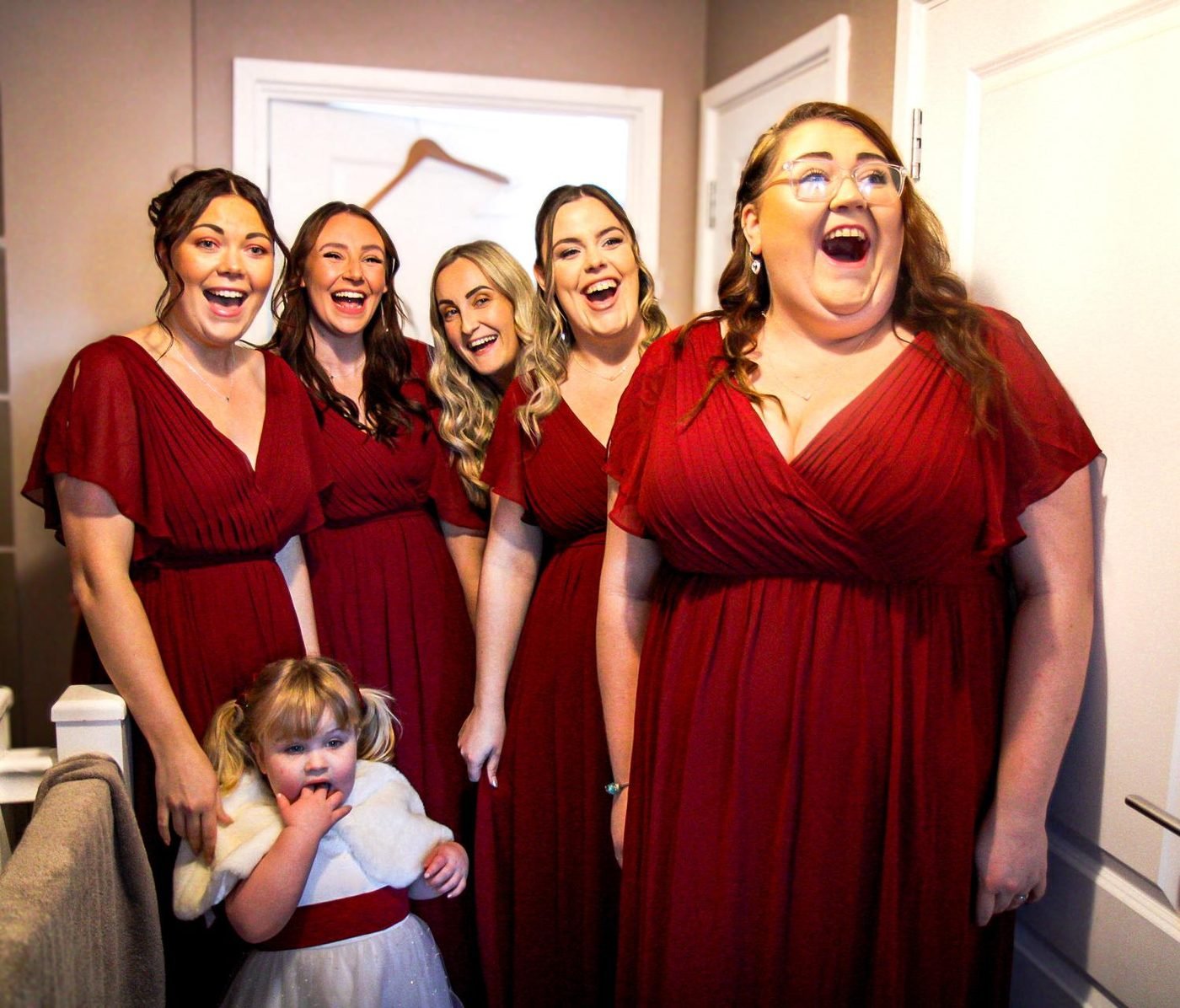Bridesmaids in red laughing together before the ceremony
