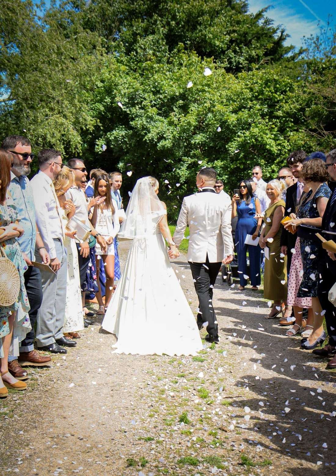 Bride and groom walking through confetti thrown by their guests