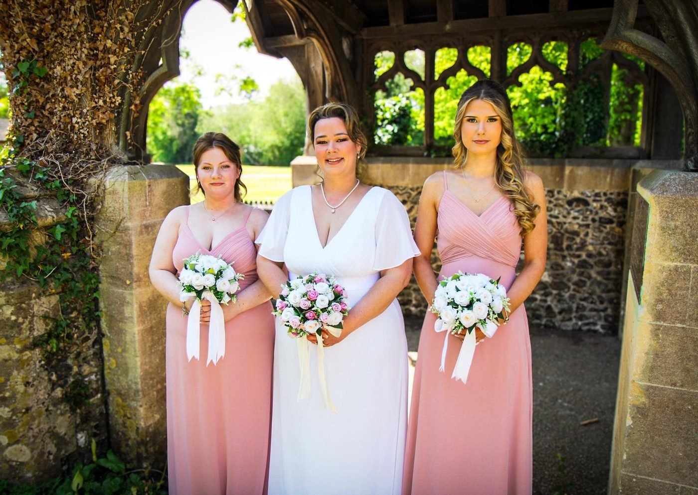 Bride with her bridesmaids under a church lychgate