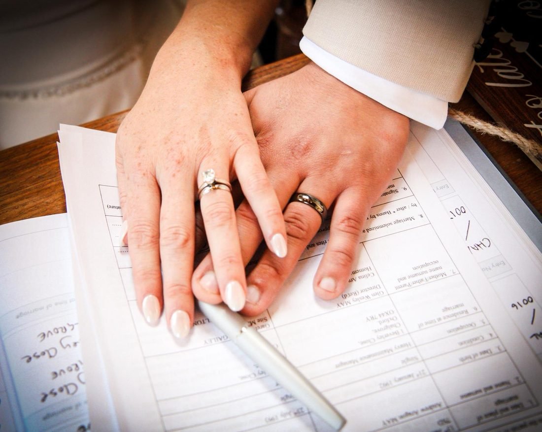 Newlyweds' hands with their rings resting on the marriage register