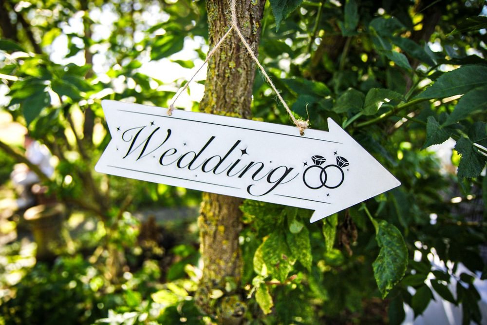 Hand-painted wedding sign hanging in the trees